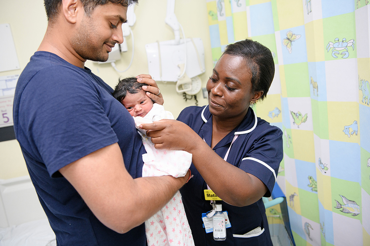 Midwife providing care to baby in father's arms