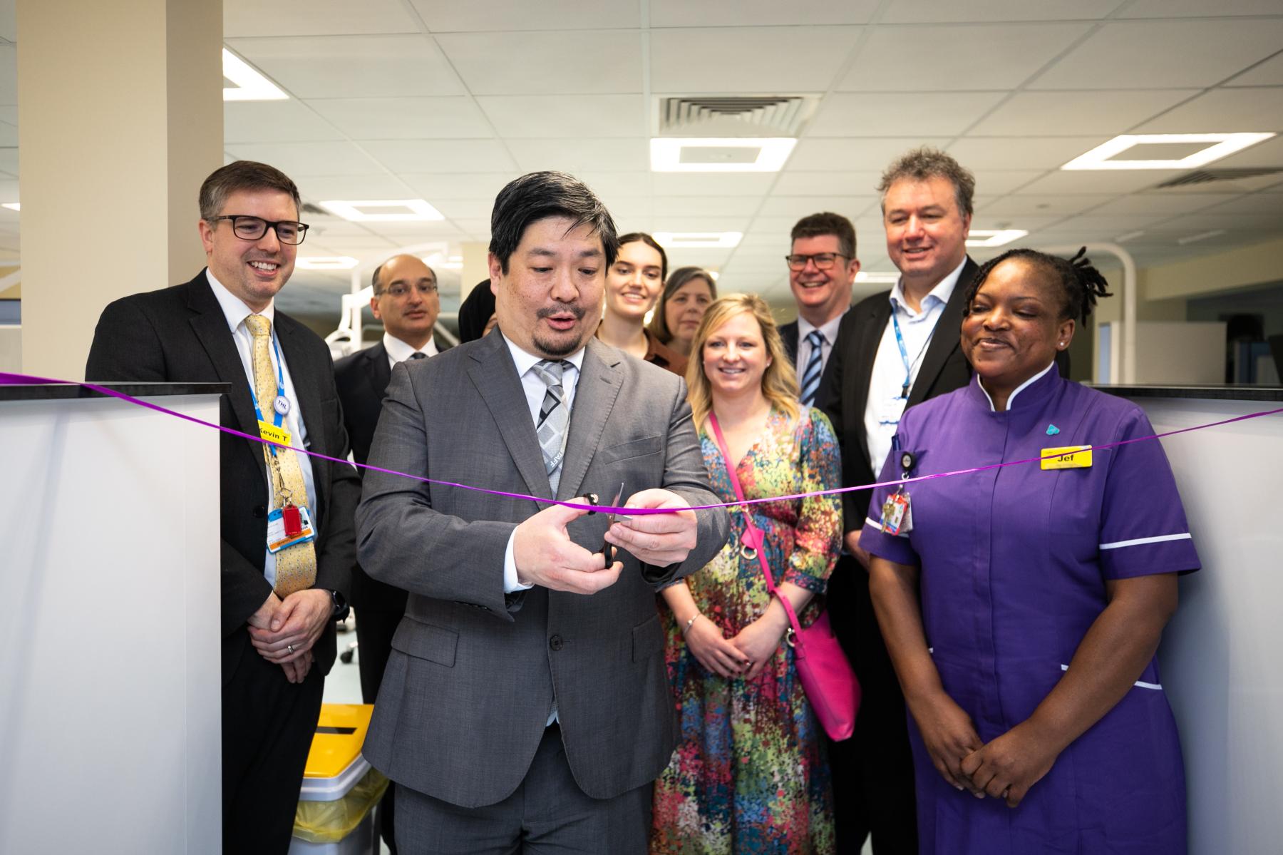 People crowded around someone cutting a ribbon