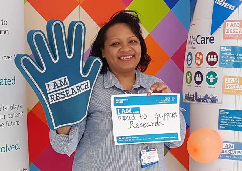 Female staff member holding an I am Research banner