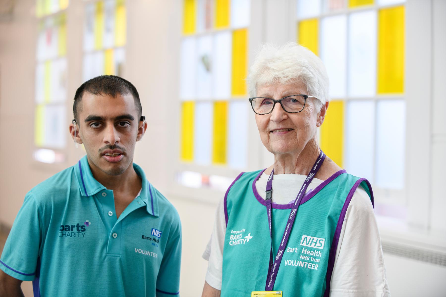 Two Barts Health volunteers stand together at Whipps Cross Hospital